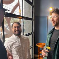 Three alumni smile and chat by bay door